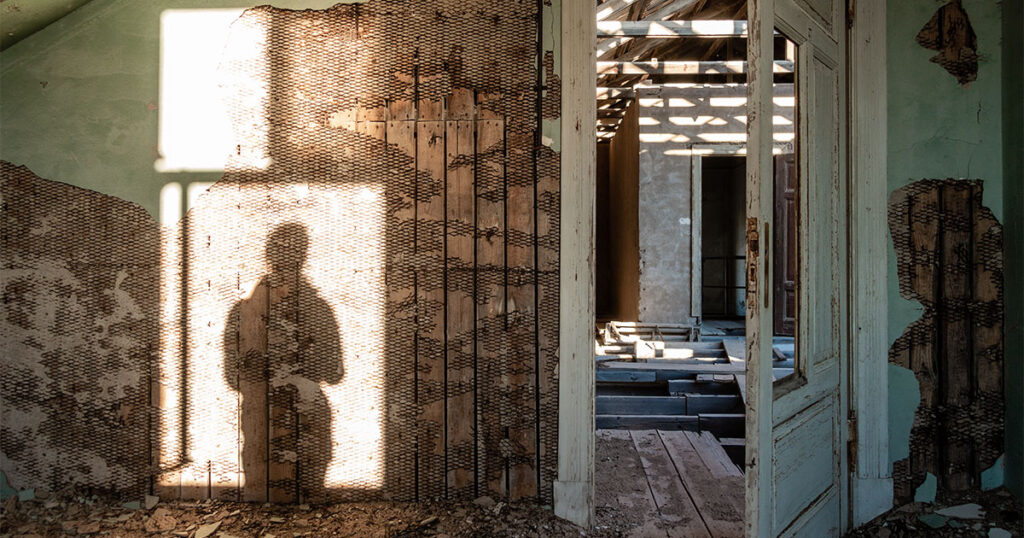 an abandoned room with the silhouette of a person in the window
