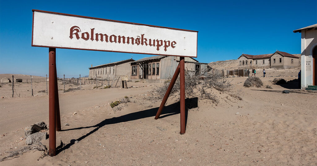 sign surrounded by sand with the german word for kolmanskop